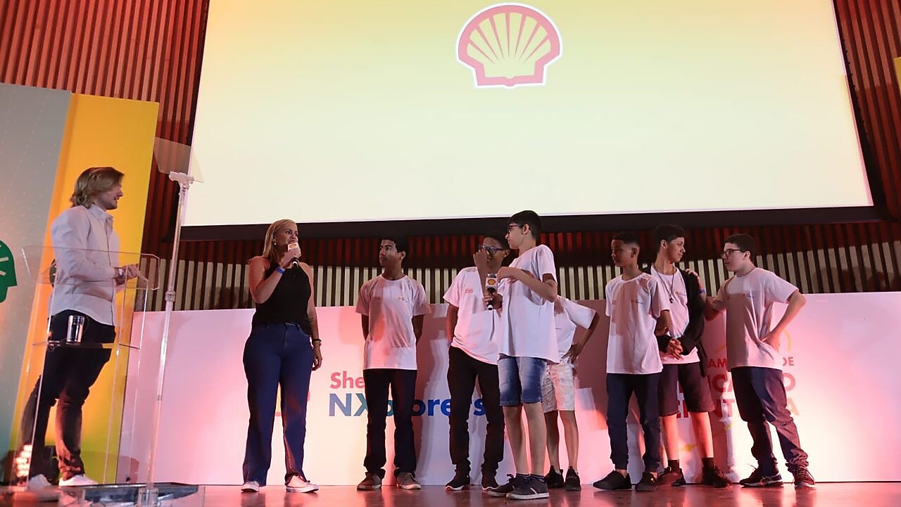 Na imagem, alunos da equipe Meninos de Ouro estão no palco da premiação.