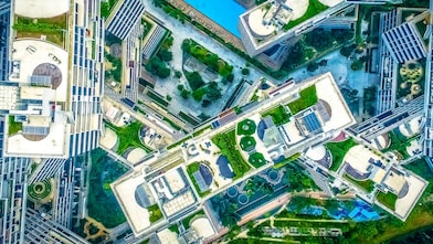 Na imagem temos a vista aérea de prédios e jardins em uma cidade
