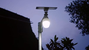 Imagem de uma lâmpada acesa em um poste de luz, com uma placa solar acima.