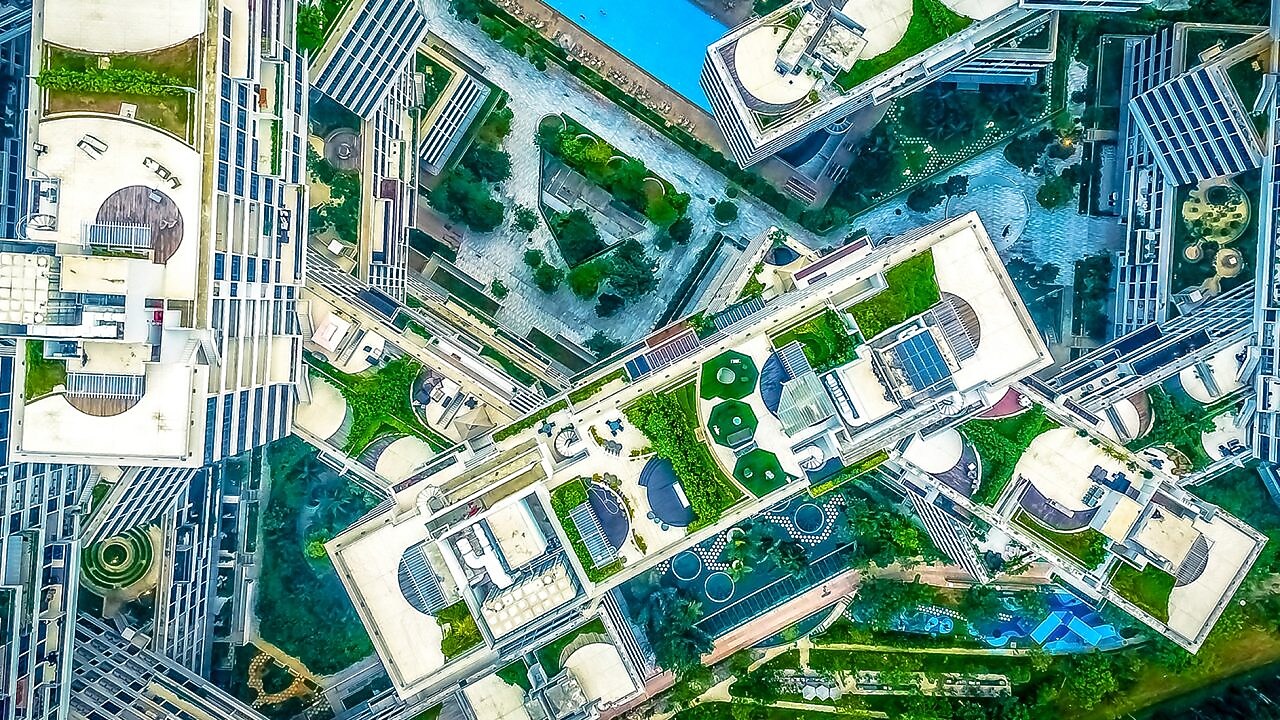 Na imagem temos a vista aérea de prédios e jardins em uma cidade