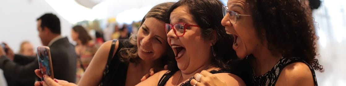 Na foto, vemos três mulheres animadas e sorridentes, enquanto posam por um selfie.