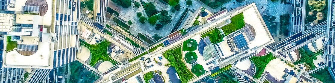 Na imagem temos a vista aérea de prédios e jardins em uma cidade
