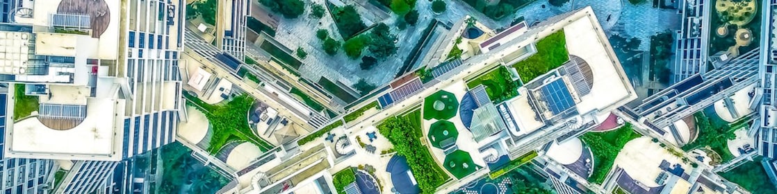 Na imagem temos a vista aérea de prédios e jardins em uma cidade
