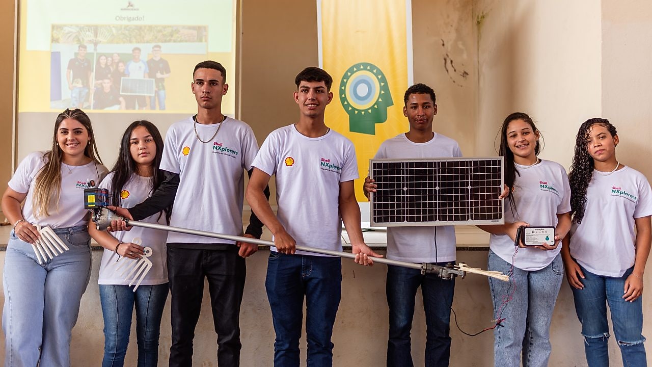 Um grupo de jovens segurando uma placa solar em um fundo neutro