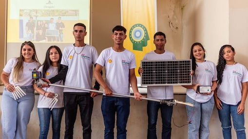 Um grupo de jovens segurando uma placa solar em um fundo neutro