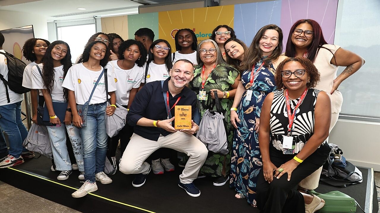 Grupo de jovens sorrindo e posando para a câmera com uma placa de madeira na mão em um evento